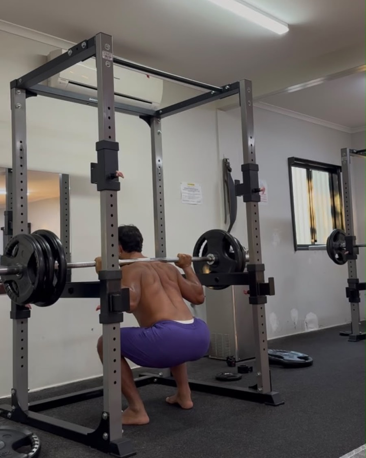 Bruno fa squat al rack in una stanza spoglia, con neon e condizionatore